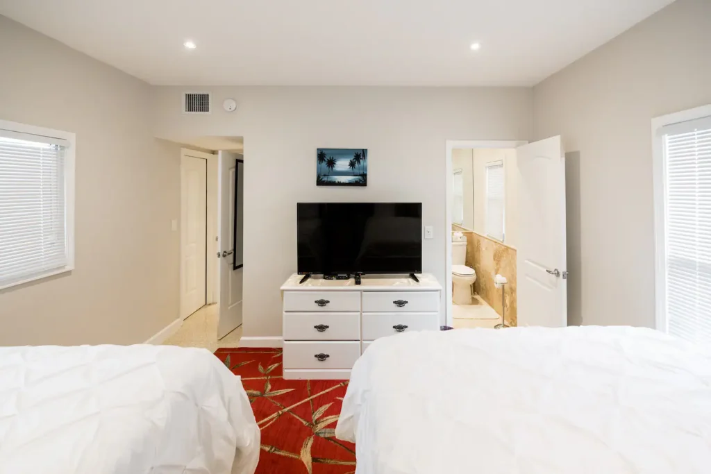Second Bedroom-view showing 55” 4K flat screen TV and entrance to modern bathroom.