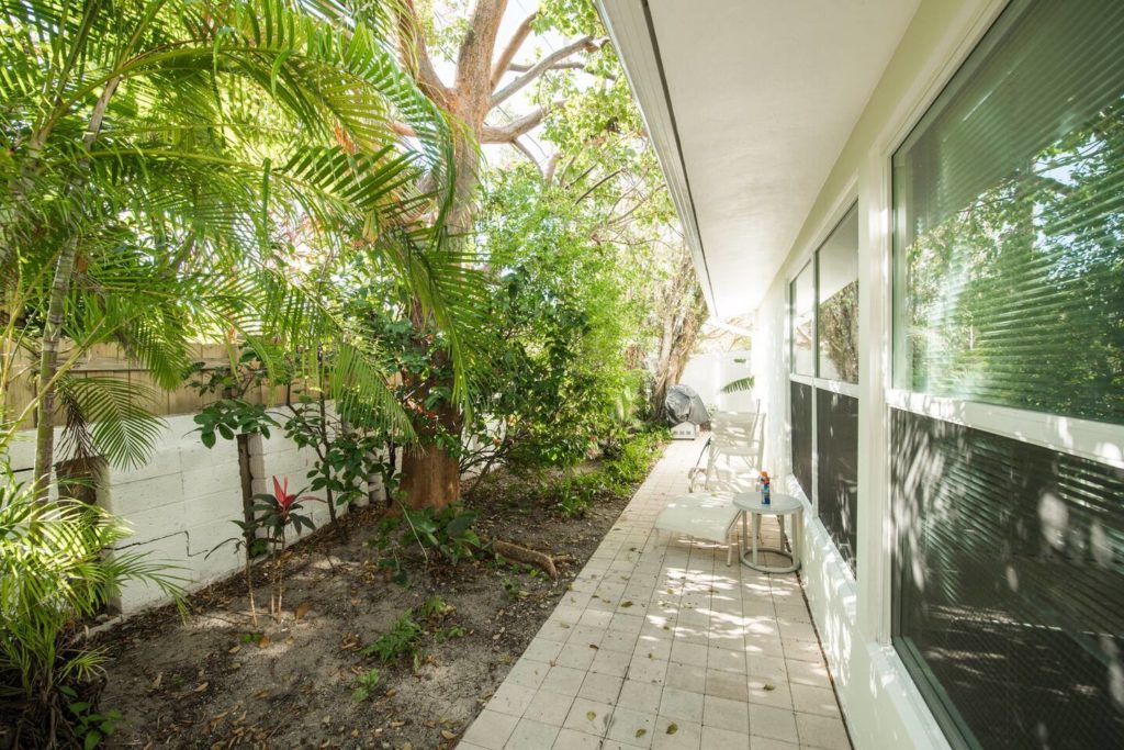 Tropical view from back of beach house. Walkway leads to gas grill and Master bedroom entrance.